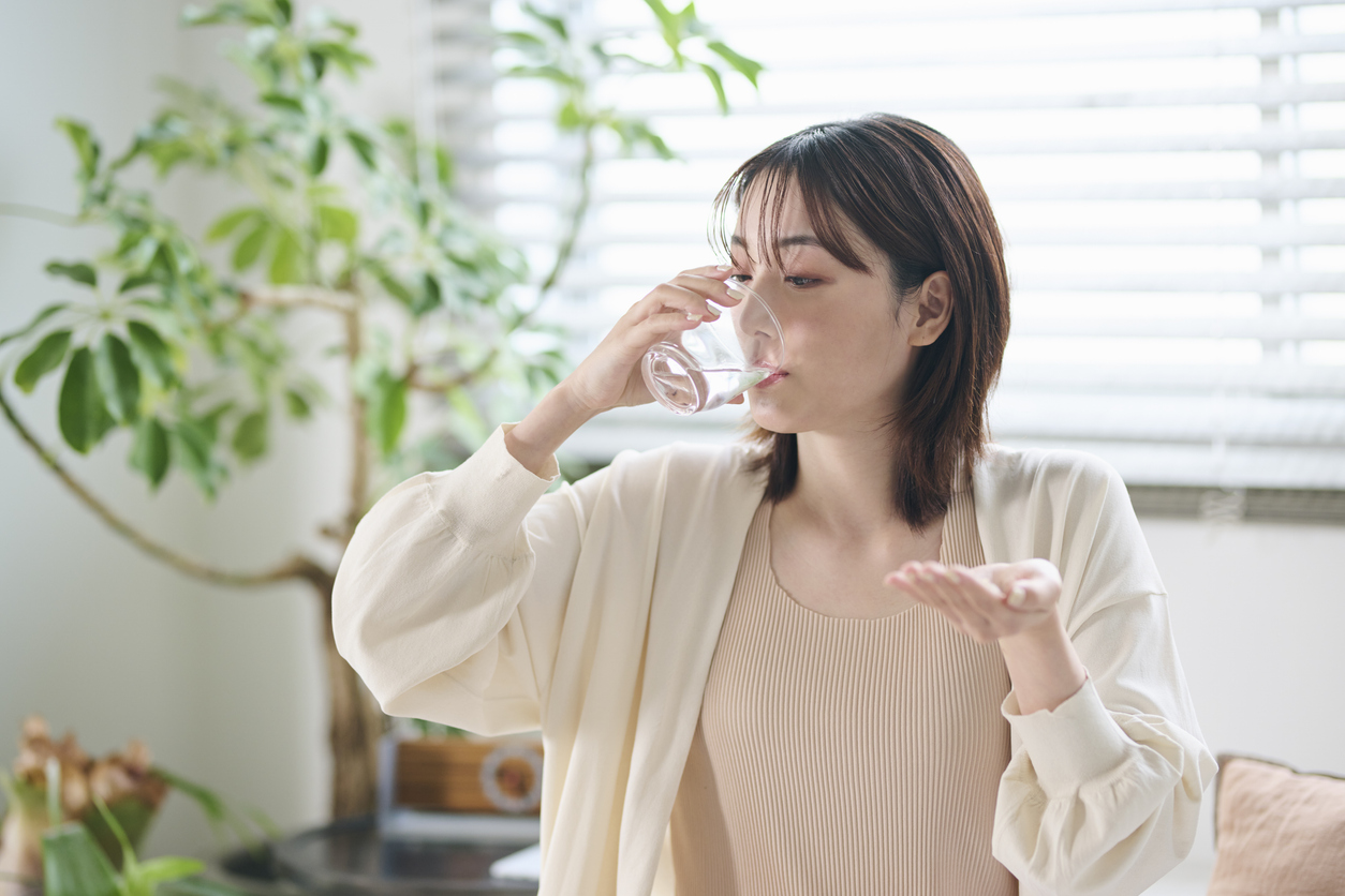 A 20-something woman taking a supplement in bed