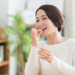 A middle-aged woman taking supplements in the living room